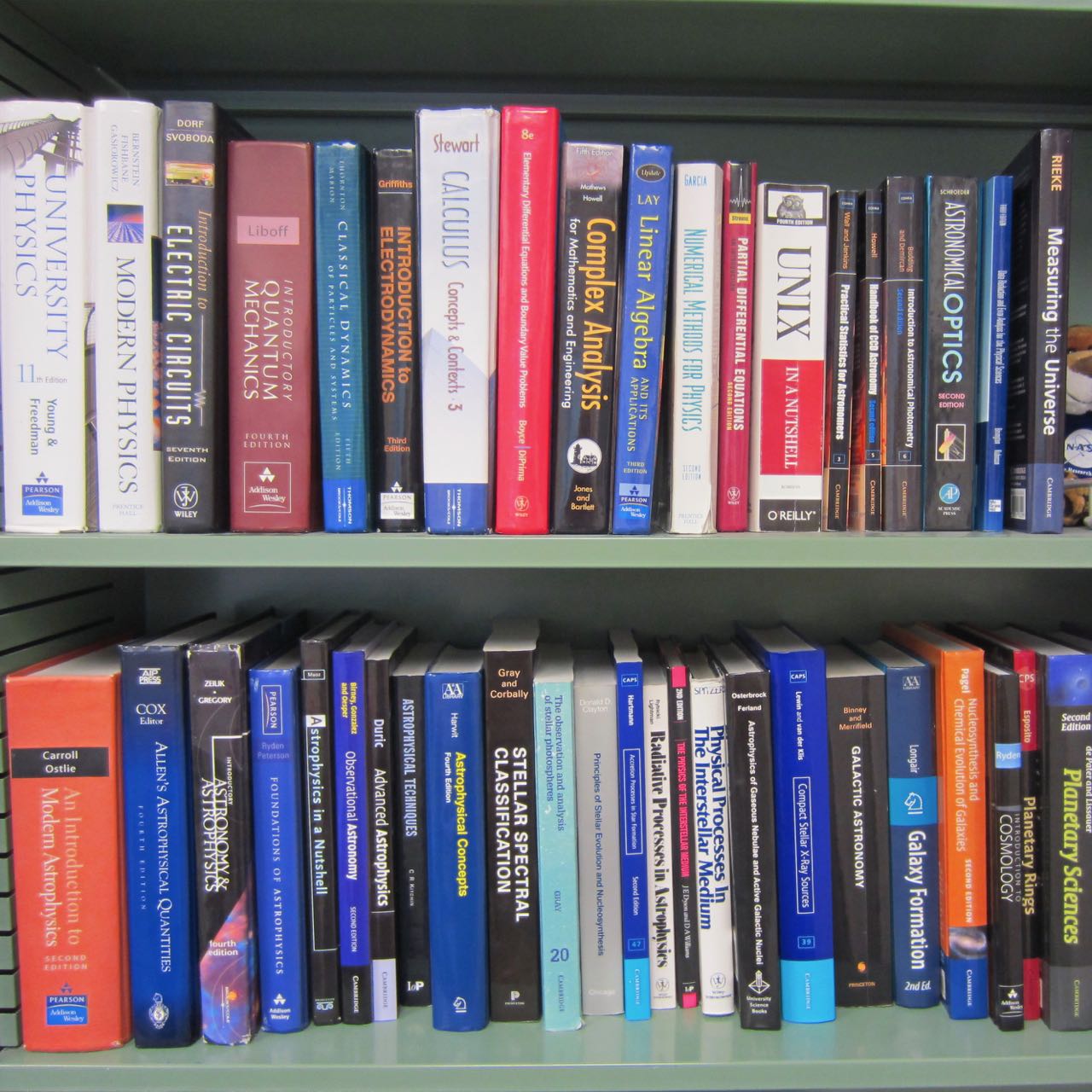A bookshelf with many textbooks for physics, math, and astronomy.